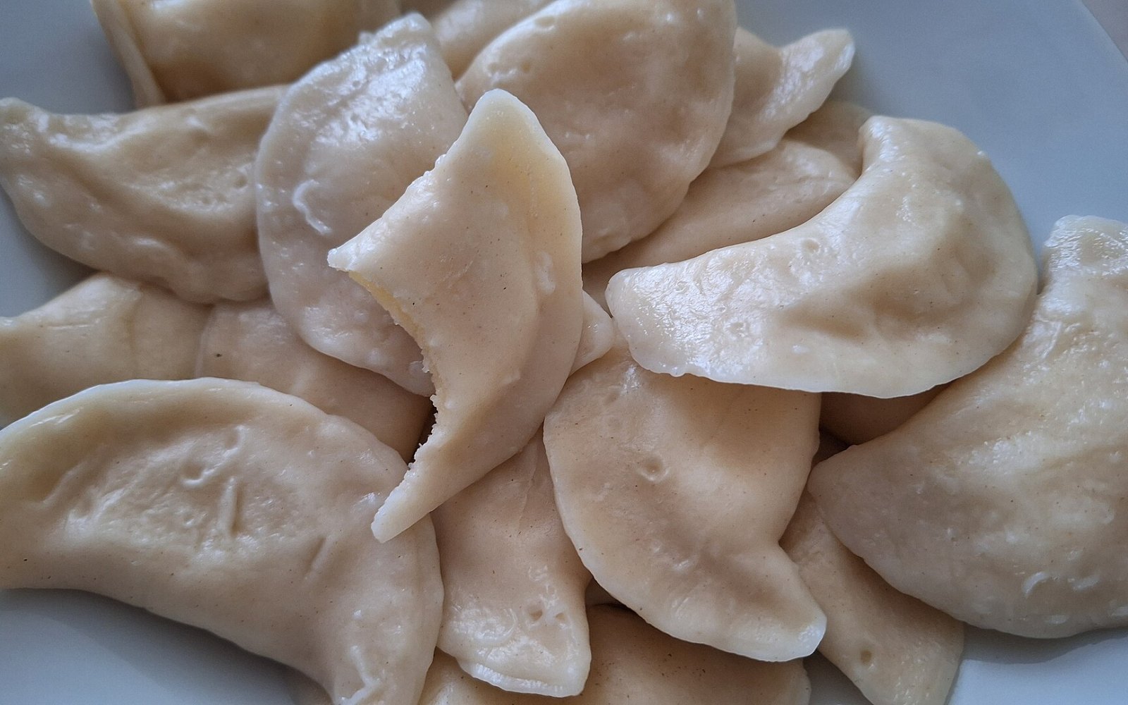 Plate of Ukrainian perogies with sour cream and caramelized onions